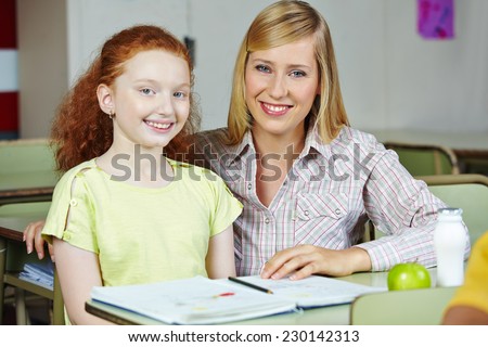 Happy teacher giving smiling girl private lessons after school