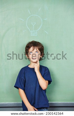 Child has an idea with lightbulb over his head drawn on a chalkboard in school