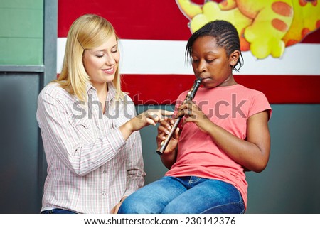 Teacher helping student to play flute in music school