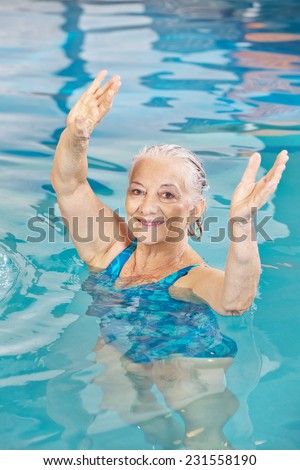 Senior woman lifting her arms in aqua fitness class in a swimming pool