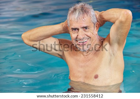 Happy senior man doing aqua fitness in swimming pool in summer