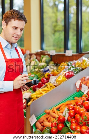 Man in organic food store ordering vegetables with mobile data acquisition terminal