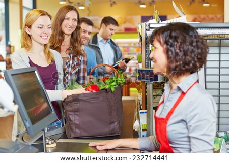 Woman with groceries waiting in line at the supermarket checkout