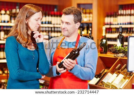 Salesman giving elderly woman advice on buying bottle of red wine