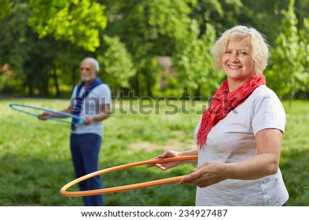 Two smiling senior people doing fitness training in a summer garden