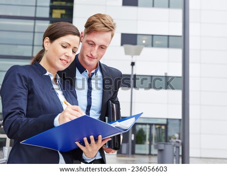 Two business people checking contract files outside in the city