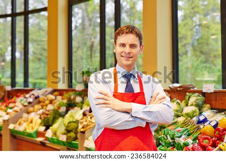 Portrait of supermarket store manager in front of fresh vegetables