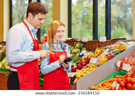 Young woman doing apprenticeship in supermarket getting help from store manager