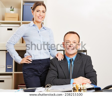 Business woman and happy man together at a desk in their office