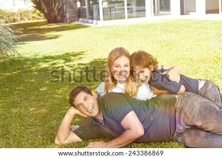 Happy family with a child laying in the garden in front of a house