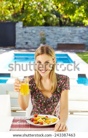 Smiling vegetarian woman eating salad with juice at lunch