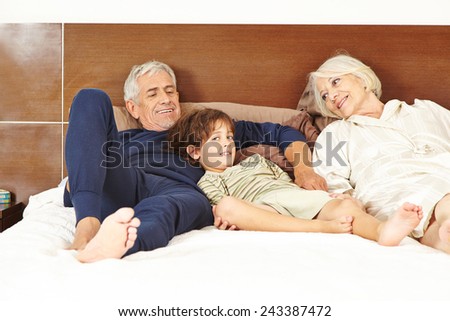 Senior couple laying with grandchildren on bed in bedroom