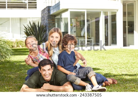 Happy family with two children laying in a garden in front of modern house