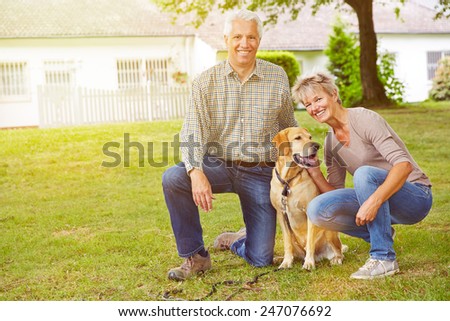 Happy senior couple sitting with house and labrador retriever in a garden