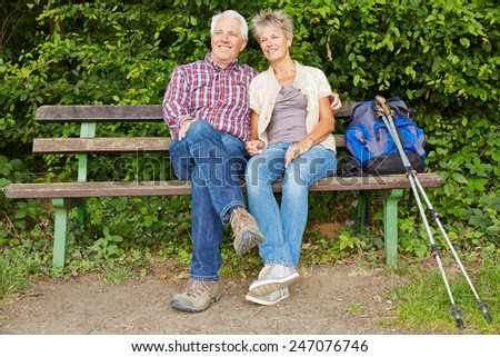 Senior couple taking break on bench while hiking in nature