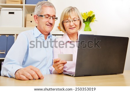 Happy senior couple doing online banking at laptop computer with credit card