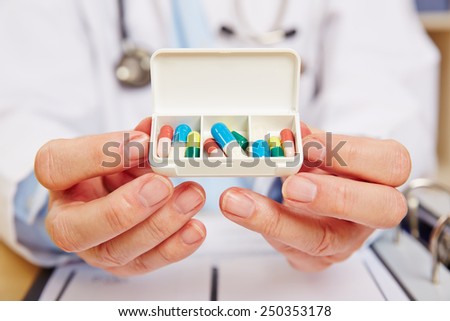 Doctor showing pill dispenser filled with medication in his hands