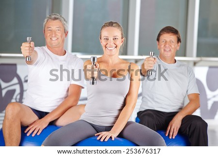 Happy group of senior people exercising with dumbbells in gym
