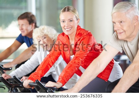 Elderly happy woman exercising in fitness center on a spinning bike