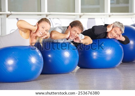 Happy group of senior people on gym balls doing back training in fitness center
