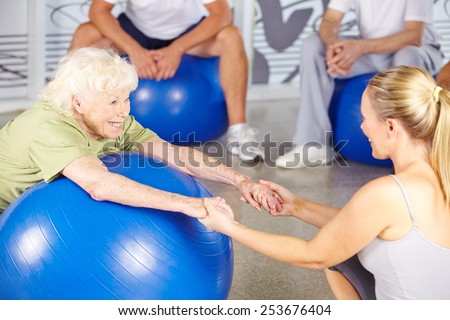 Happy senior woman with fitness instructor in rehab center