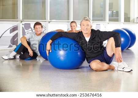 Man sitting in group of senior people with gym ball in a fitness center