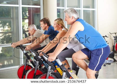 Spinning class with four happy senior people in a gym