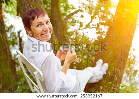 Relaxed senior woman taking a break with cup of tea in her garden