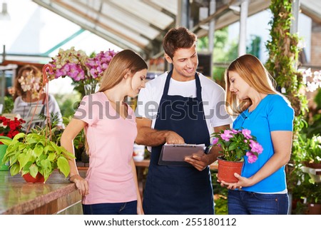 Gardener in a nursery shop giving advice to two female customers