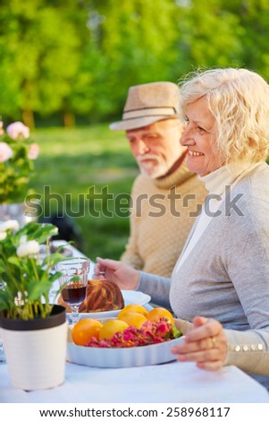 Happy senior couple eating cake in a garden in summer