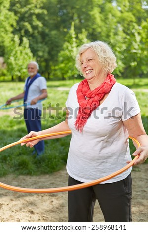 Two happy senior people doing sports with hoop in nature