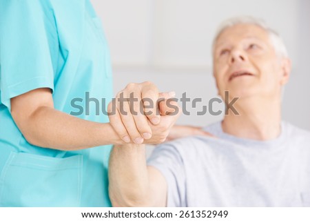 Nursing assistant holding hand of senior man for support