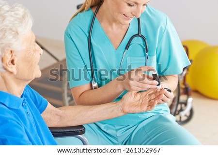 Geratric nurse monitoring blood sugar of senior woman with diabetes