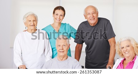Happy group of senior citizens in nursing home with geriatric nurse