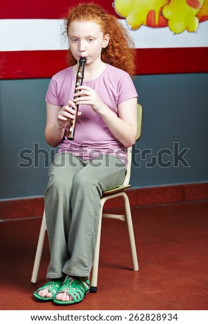 Girl playing flute at music lessons in music school