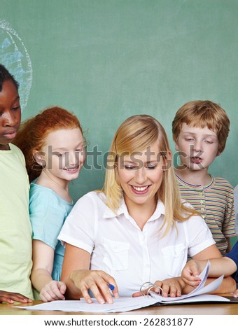 Elementary school students looking at teacher working in class at her desk