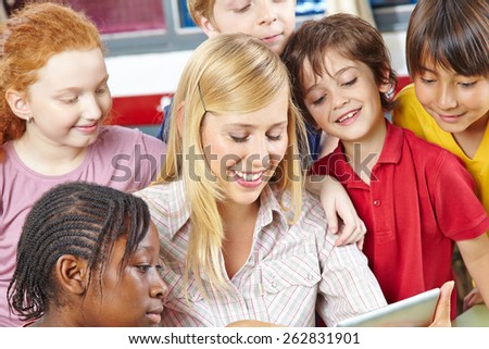 Teacher and students looking at tablet computer in elementary school class