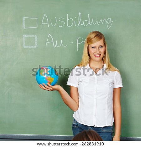 Woman with globe in front of chalkboard with German words for Apprenticeship and Au-Pair written on it