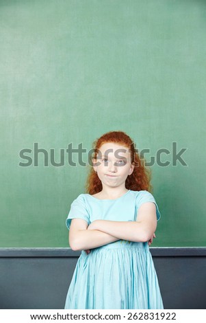 Pensive girl in front of a chalkboard in elementary school