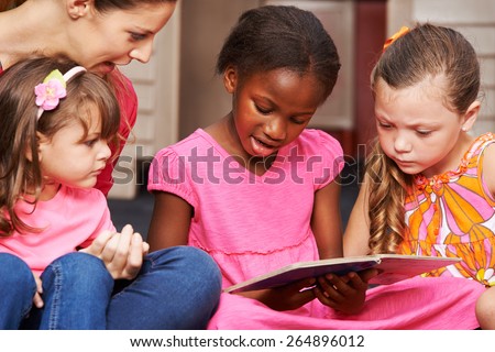 Children learning to read with nursery teacher in preschool