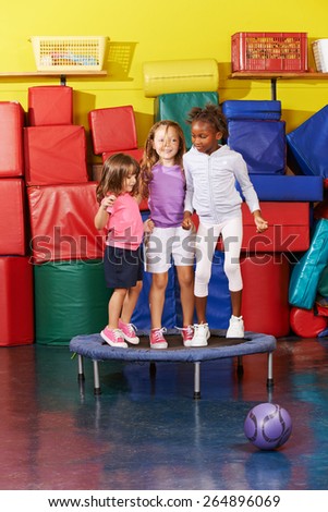 Three children jumping on trampoline together in gym of a kindergarten