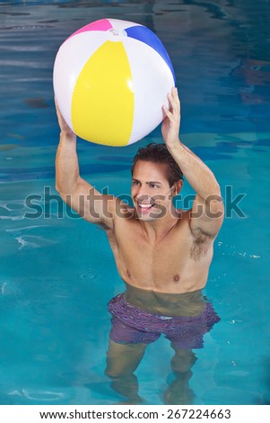 Happy man in swimming pool playing with a water ball
