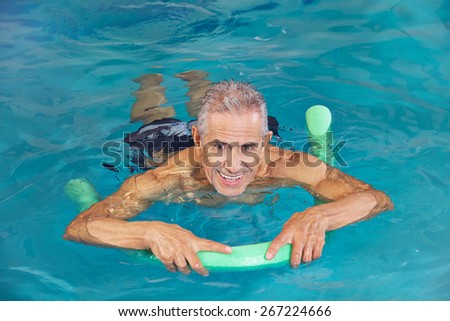 Old man swimming in water of hotel pool with swim noodle