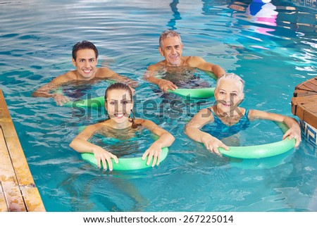 Group of happy people with swim noodles doing aqua fitness class in swimming pool