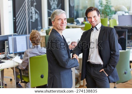 Two smiling business people giving handshake in the office