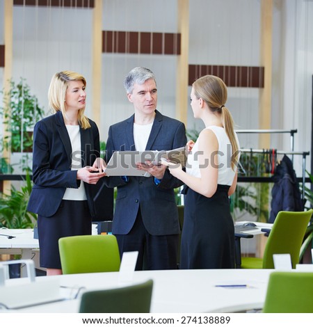 Group of business people in office talking to each other with files
