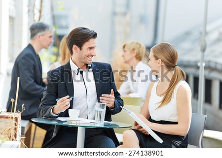 Business man and woman talking outdoors in a coffee shop with each other
