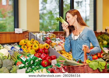 Woman smelling fresh fennel while shopping in a supermarket