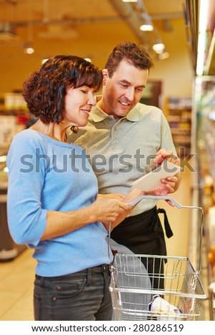 Friendly salesman helping elderly woman in supermarket finding her groceries