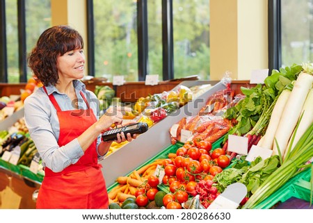Salesperson counting vegetables with mobile data registration terminal for a new delivery in a supermarket